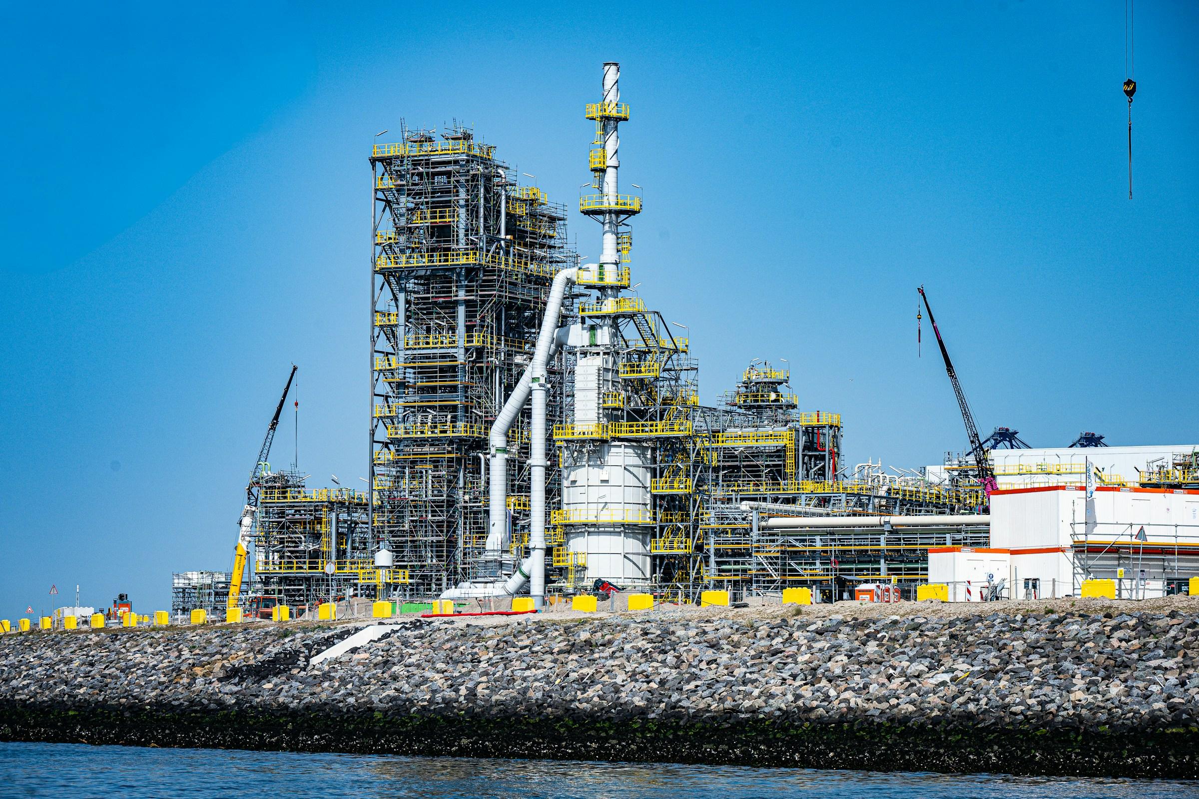 A process plant structure with columns and pipe racks beside the sea
